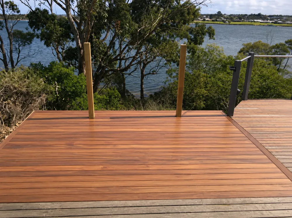 Fertig verlegte Holzterrasse mit Edelstahl-Glasgeländer und Blick über den See